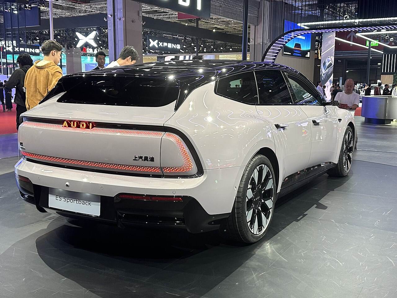Biały AUDI E5 Sportback widziany z tylnego narożnika, z podświetlanym napisem AUDI i tablicą modelu