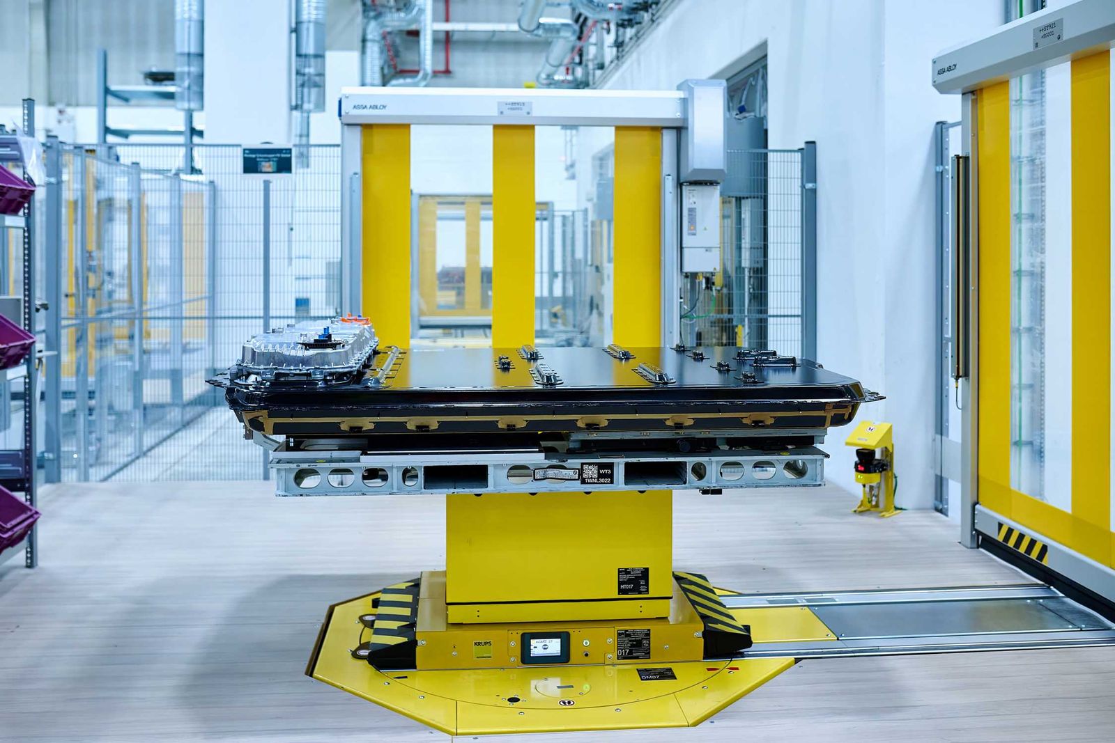 Bateria BMW Gen6 — płaski pakiet wysokonapięciowy na stanowisku transportowym w hali produkcyjnej