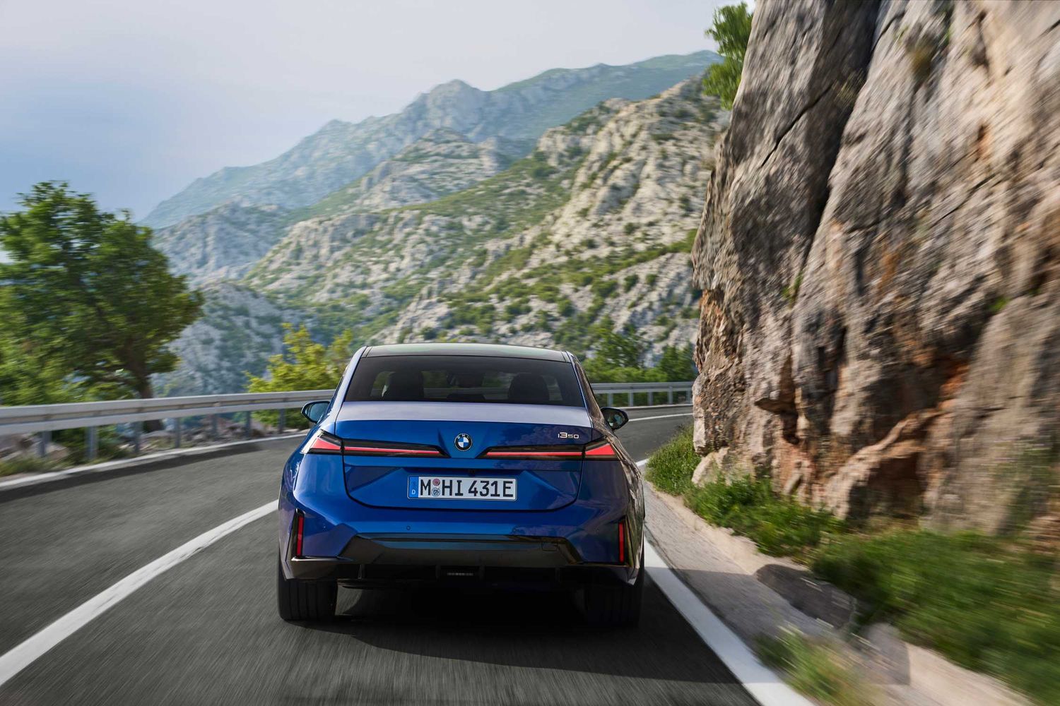 Niebieskie BMW i3 50 xDrive widziane od tyłu na górskiej drodze