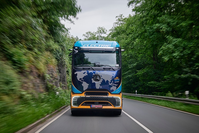 Elektryczna ciężarówka Mercedes-Benz eActros 600 ekspedycyjny z okleiną w formie mapy świata na drodze