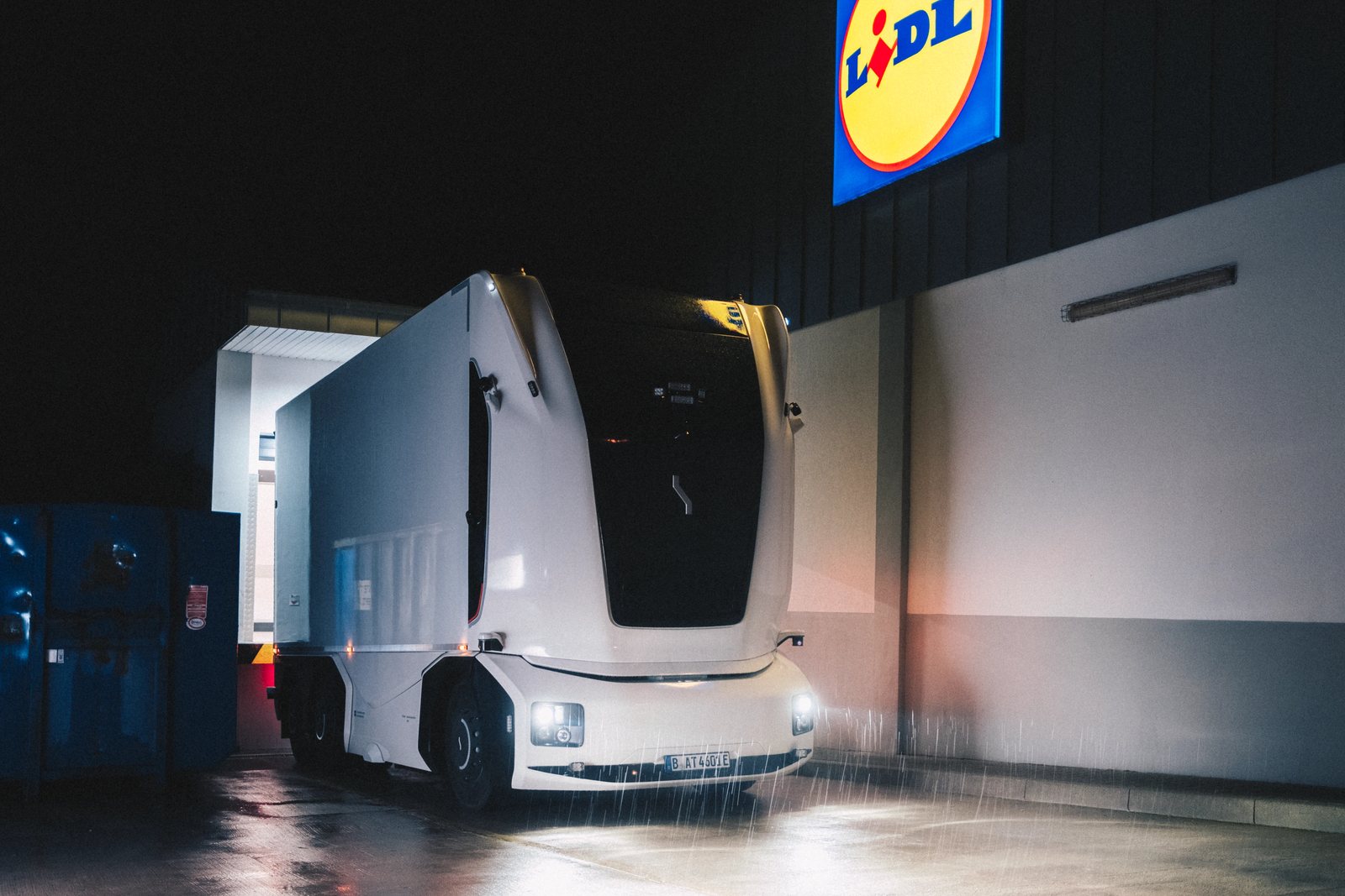Autonomiczna ciężarówka bez kabiny Einride podczas nocnego załadunku przed sklepem Lidl w Niemczech