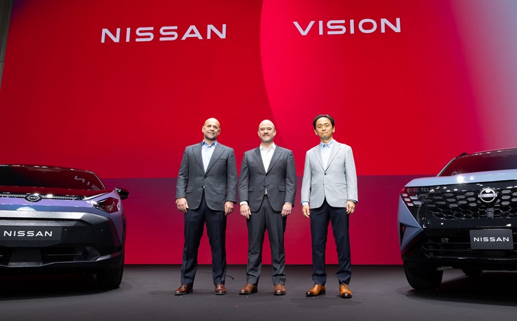 Trzech przedstawicieli Nissana podczas prezentacji modelu PIXO, za nimi napis Nissan Vision i dwa samochody marki