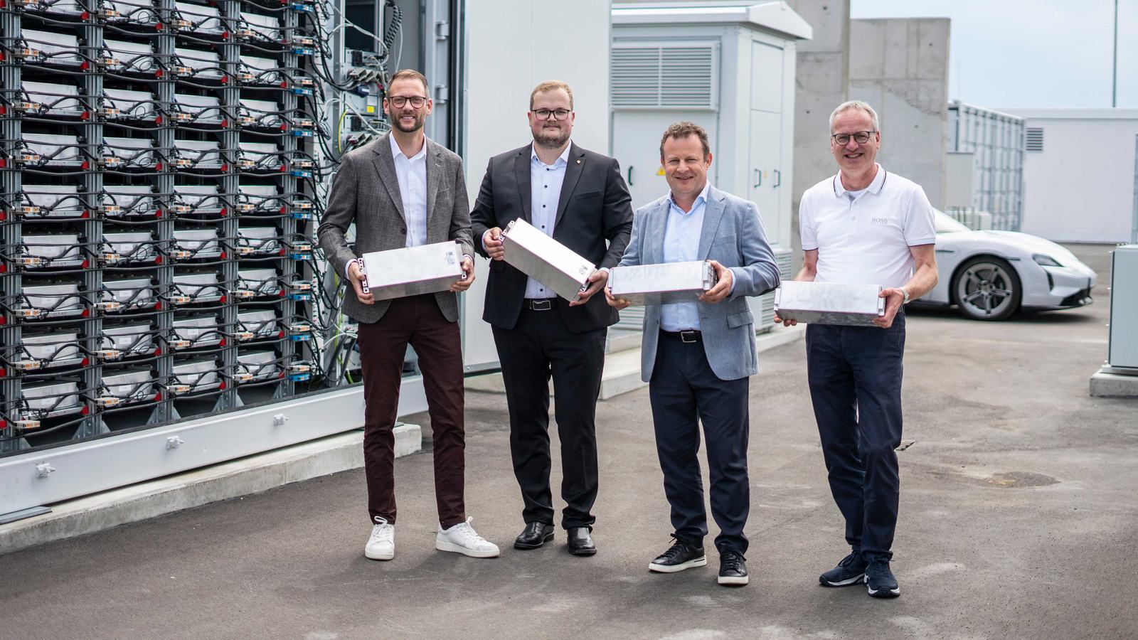 Moduły baterii Porsche Taycan trzymane przez zespół przed magazynem energii — recykling baterii Porsche