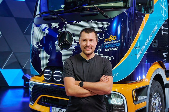Kierowca Tobias Wagner, znany jako Elektrotrucker, przed elektryczną ciężarówką eActros 600 z napisem 100 procent electric