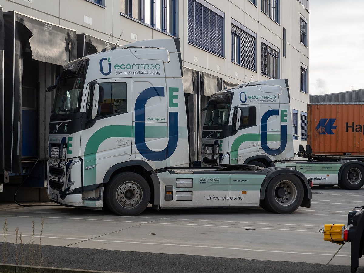 Elektryczna ciężarówka z naczepą przy rampie przeładunkowej — ładowanie e-ciężarówek w bazie logistycznej
