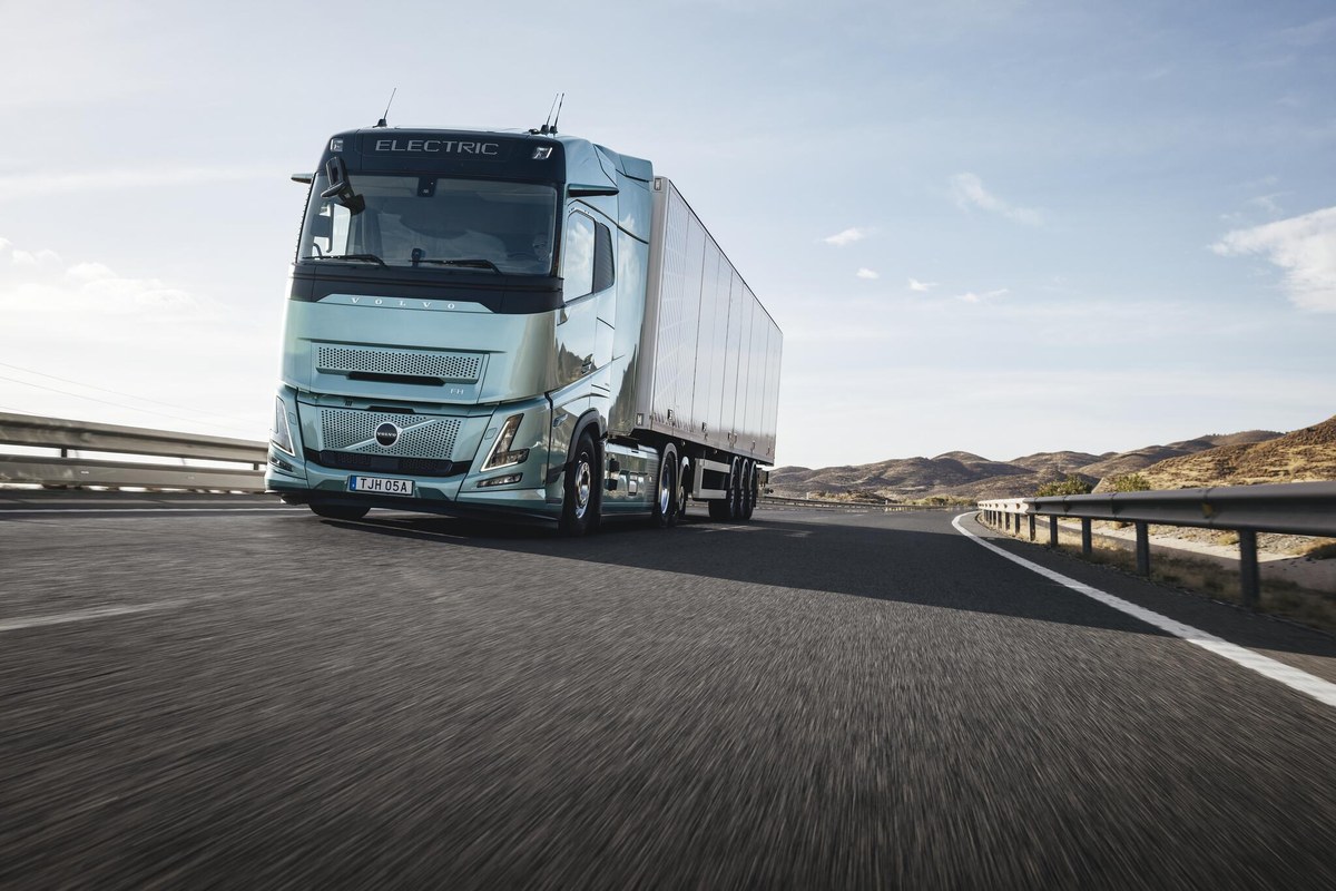 Elektryczny ciągnik Volvo FH Electric z naczepą na drodze wśród wzgórz