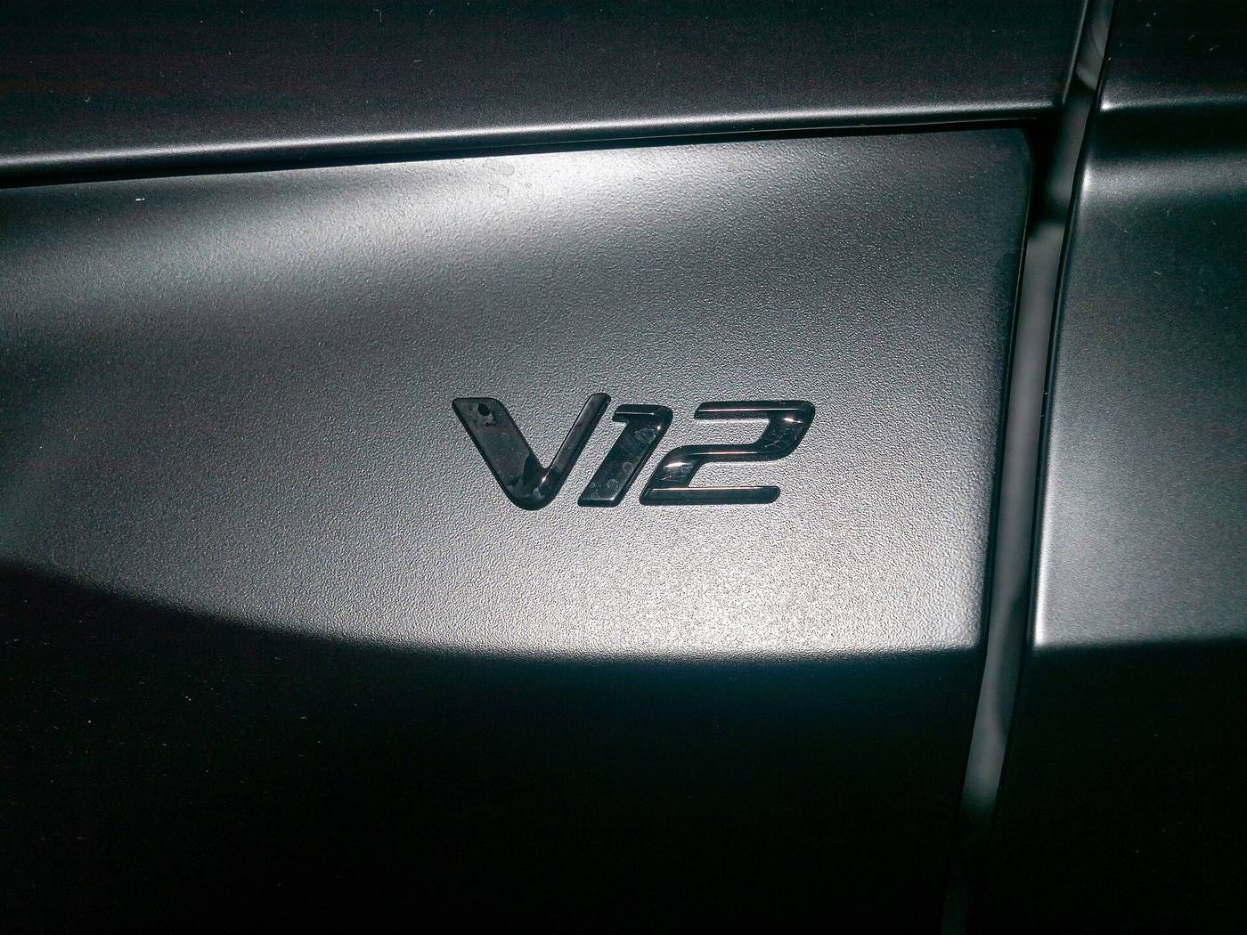 Emblemat V12 na błotniku ciemnego Aston Martina