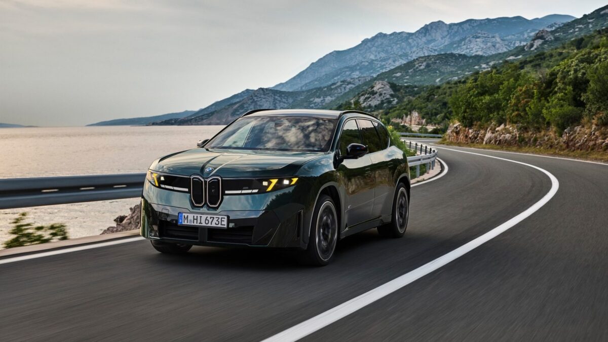 BMW iX3 M60 xDrive, ciemnozielony elektryczny SUV Neue Klasse, podczas jazdy nadmorską drogą