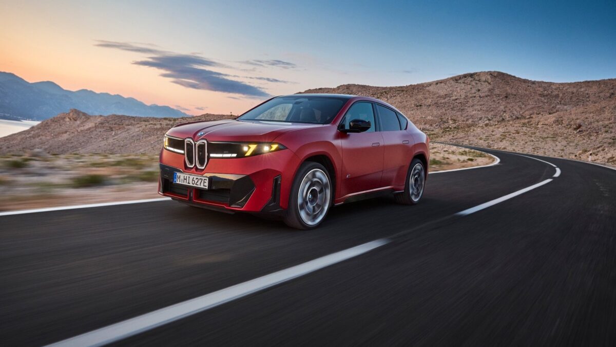 BMW iX4 M60 xDrive w czerwonym lakierze podczas jazdy po górskiej drodze