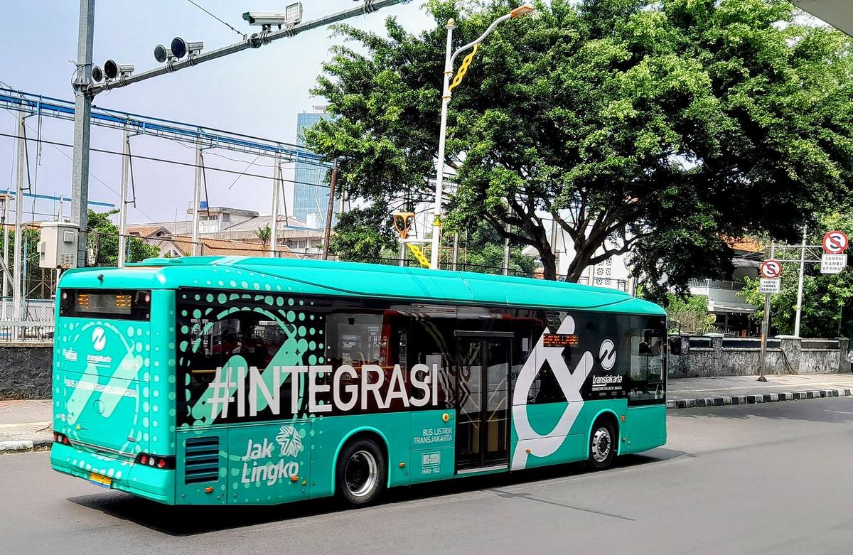 Elektryczny autobus BYD K9 w barwach TransJakarta widziany z boku na miejskiej ulicy
