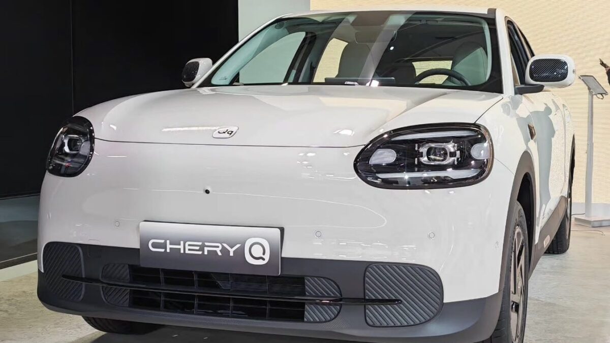 Biały Chery Q, mały elektryk, widok z przodu na tle ściany salonu
