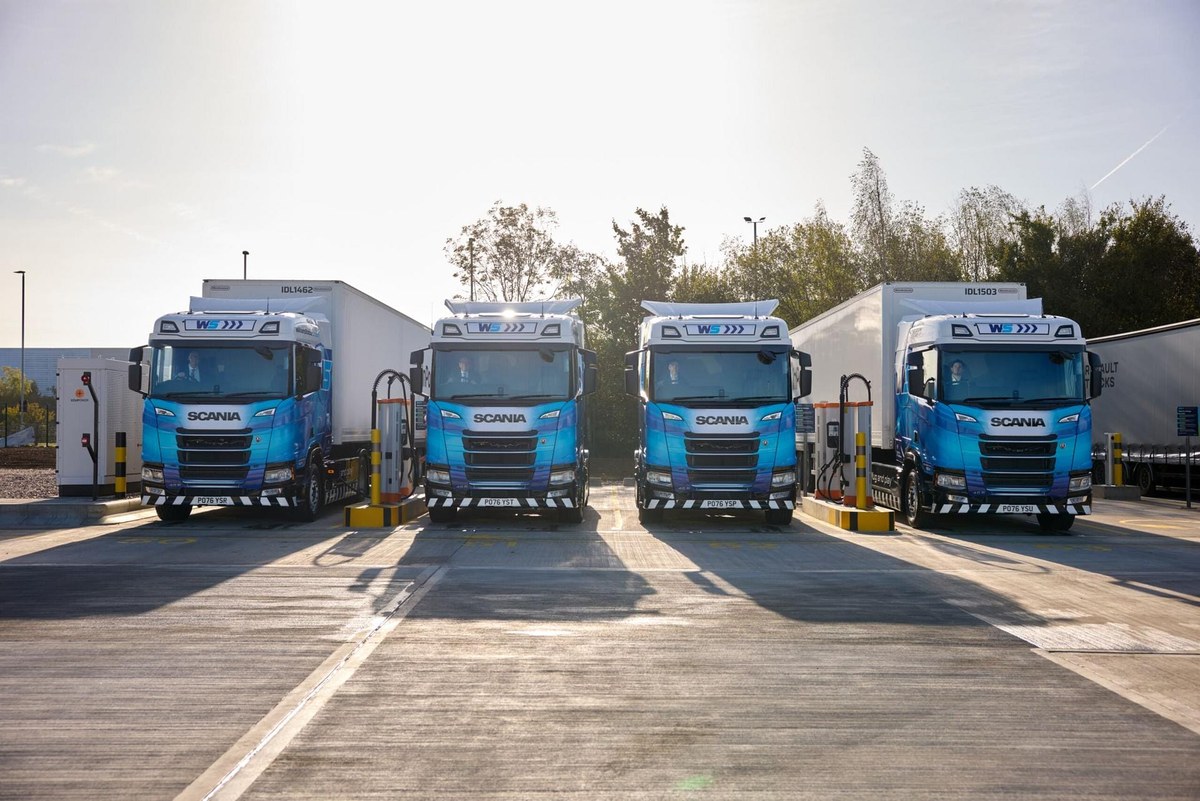 Cztery niebieskie elektryczne Scanii z naczepami na stanowiskach ładowania w hubie Electroway