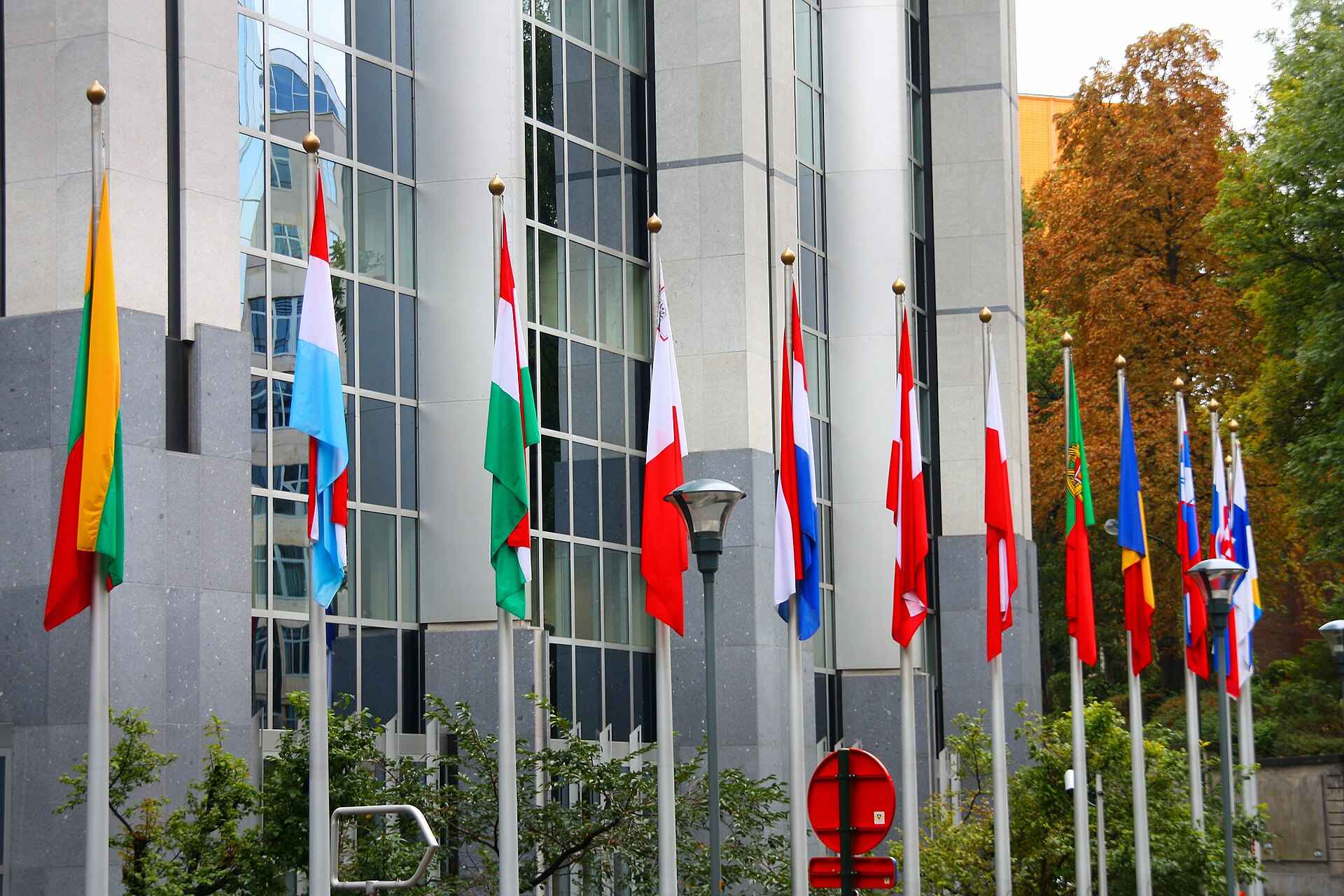 Flagi państw Unii Europejskiej na masztach przed budynkiem instytucji unijnych w Brukseli