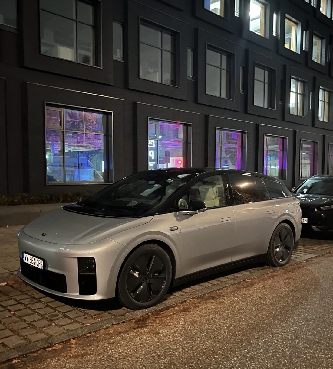 Srebrny Li Auto i6 z francuską tablicą rejestracyjną zaparkowany przy europejskim budynku