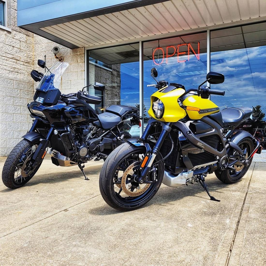 Żółty motocykl LiveWire obok Harleya-Davidsona Pan America przed salonem