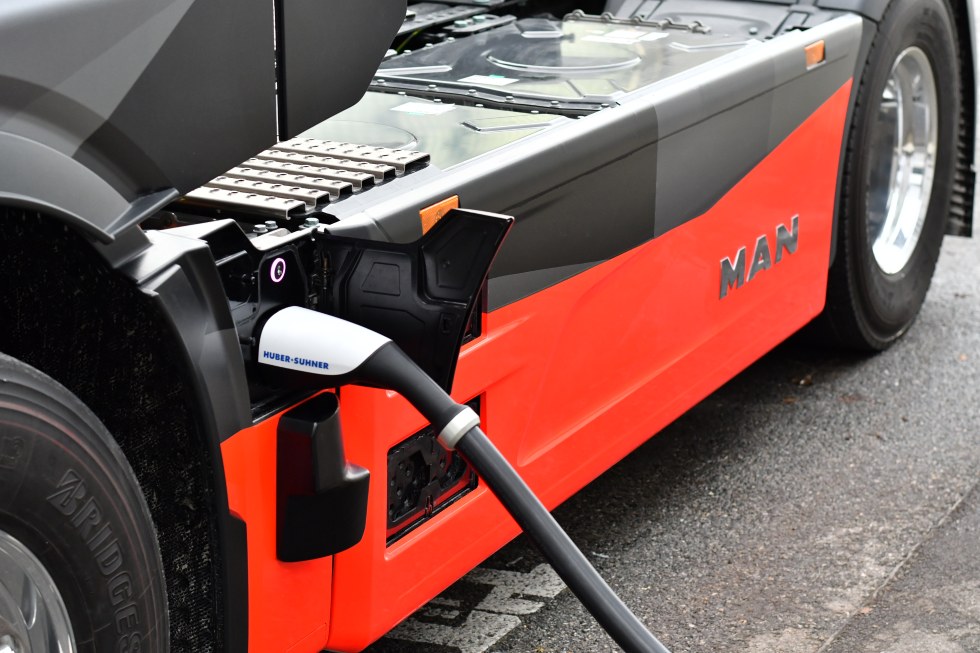 Czerwony MAN eTruck podczas ładowania megawatowego z podłączoną wtyczką MCS
