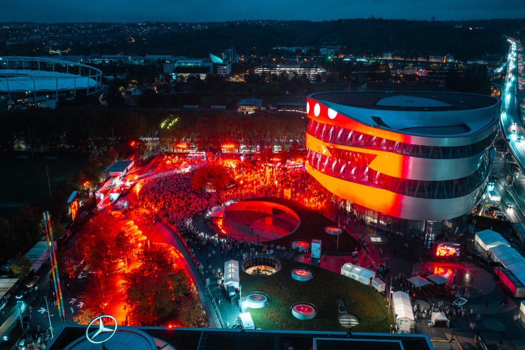 Podświetlone na czerwono muzeum Mercedes-Benz w Stuttgarcie i tłum gości podczas festiwalu THE 140