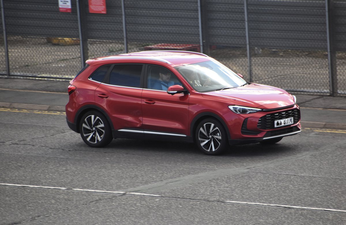 Szary SUV MG ZS Hybrid+ zaparkowany przy krawężniku na europejskiej ulicy