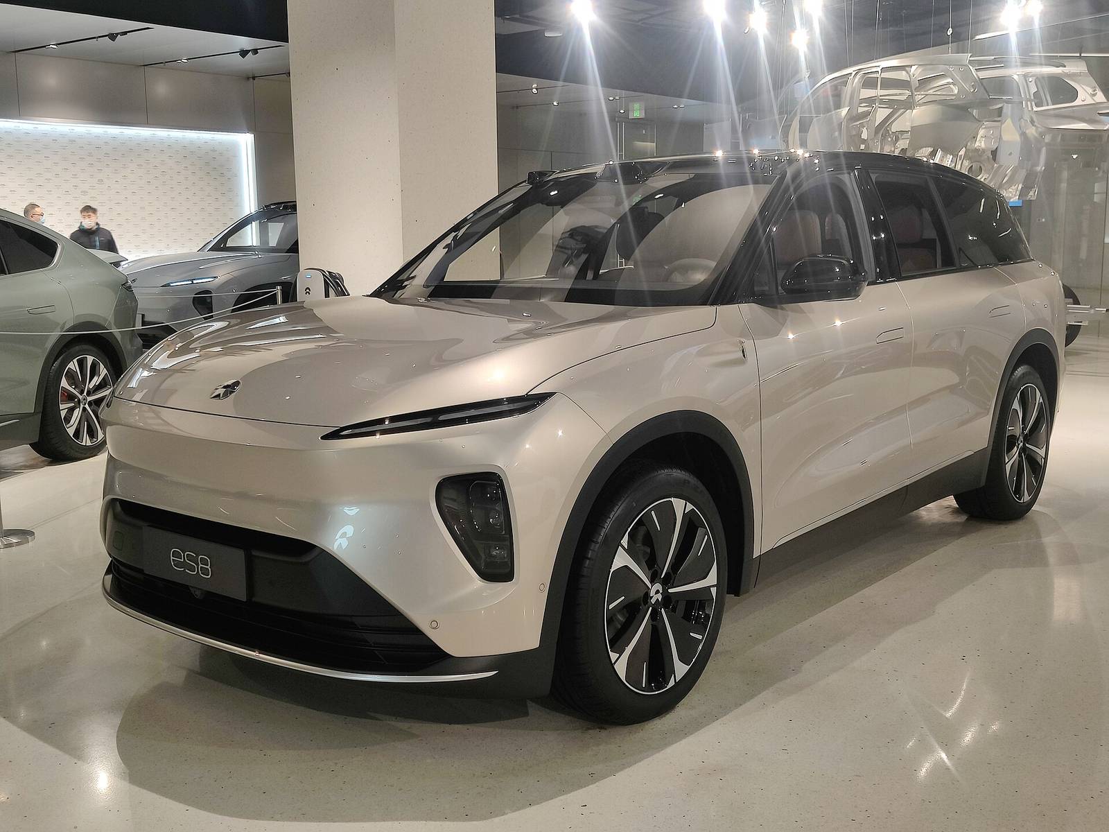 NIO ES8 drugiej generacji w jasnym lakierze na wystawie – poprzednia generacja modelu