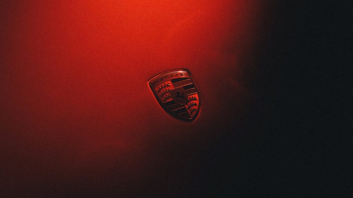 Herb marki Porsche na karoserii oświetlonej czerwonym światłem — strategia Porsche do 2035 roku