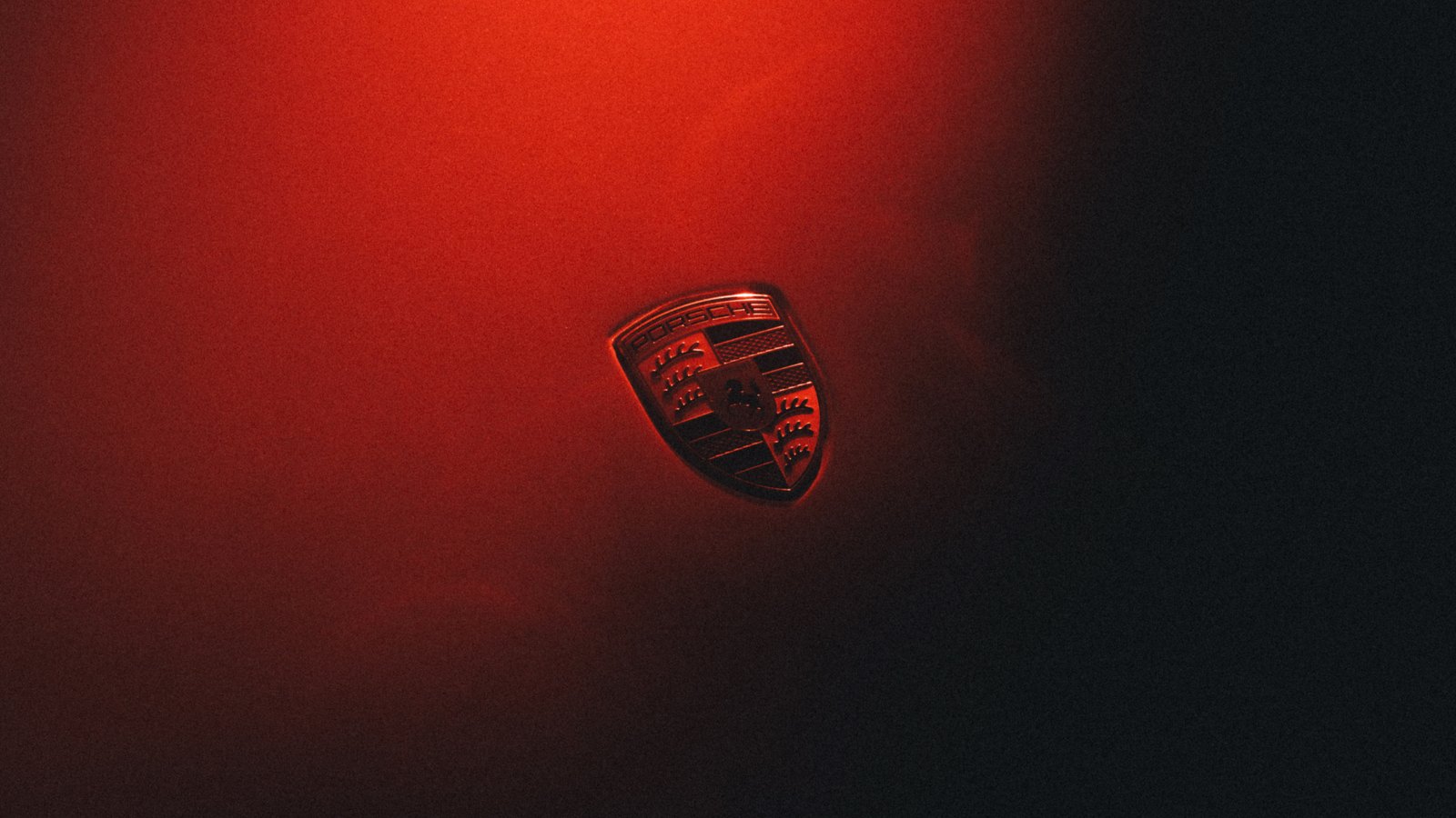 Herb marki Porsche na karoserii oświetlonej czerwonym światłem — strategia Porsche do 2035 roku