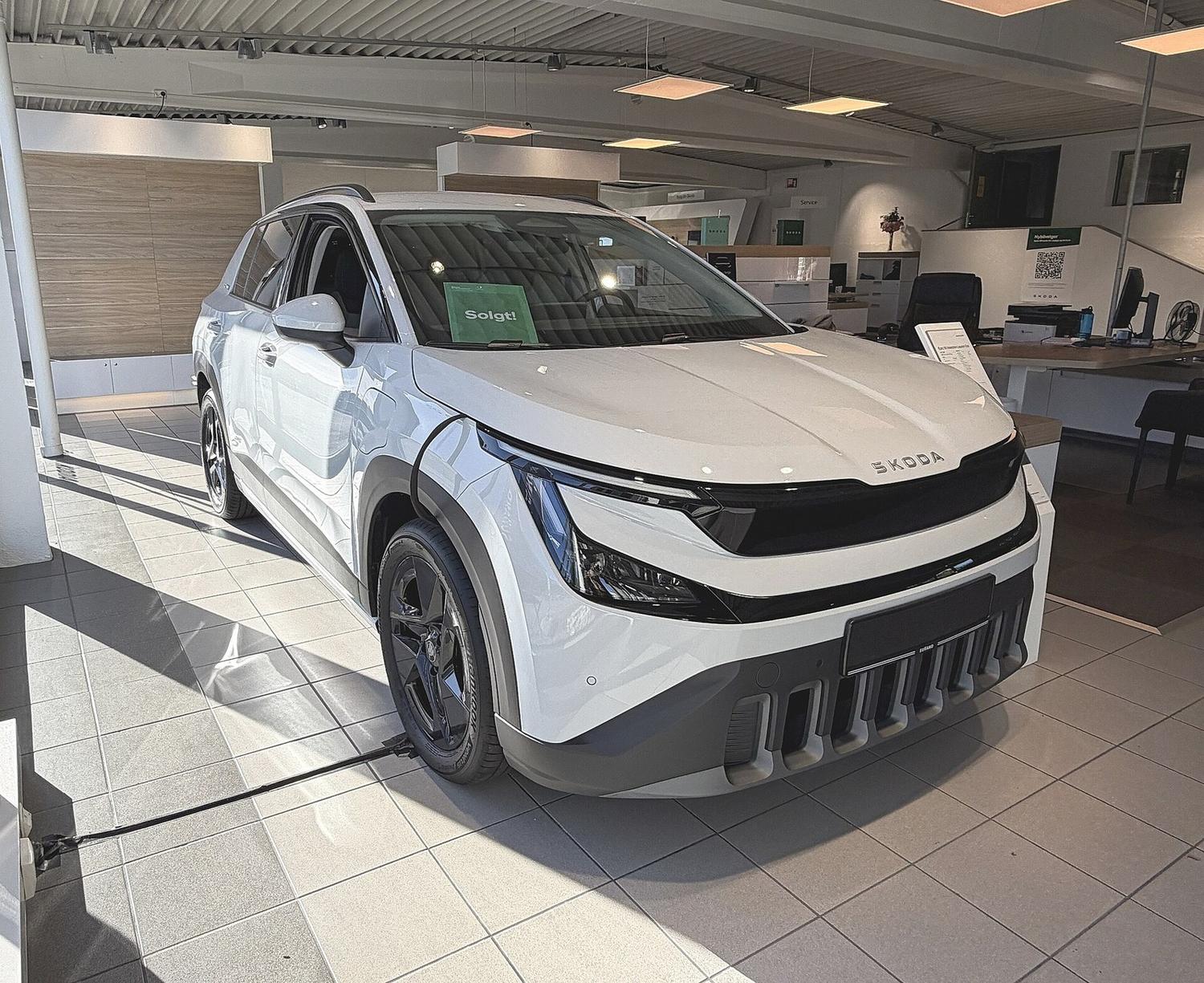 Biała Škoda Epiq w salonie, widok na przedni pas i reflektory