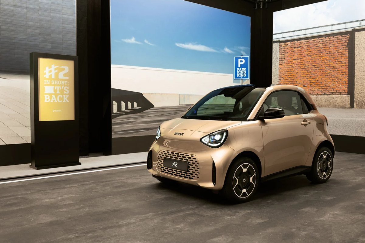smart #2 Premium w złotym lakierze metallic — widok z boku na tle architektury miejskiej