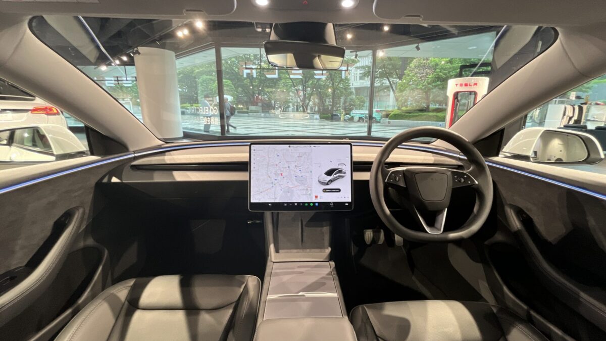 Kokpit Tesli z ekranem dotykowym, na którym kierowca ustawia pakiet Tesla Assisted Driving