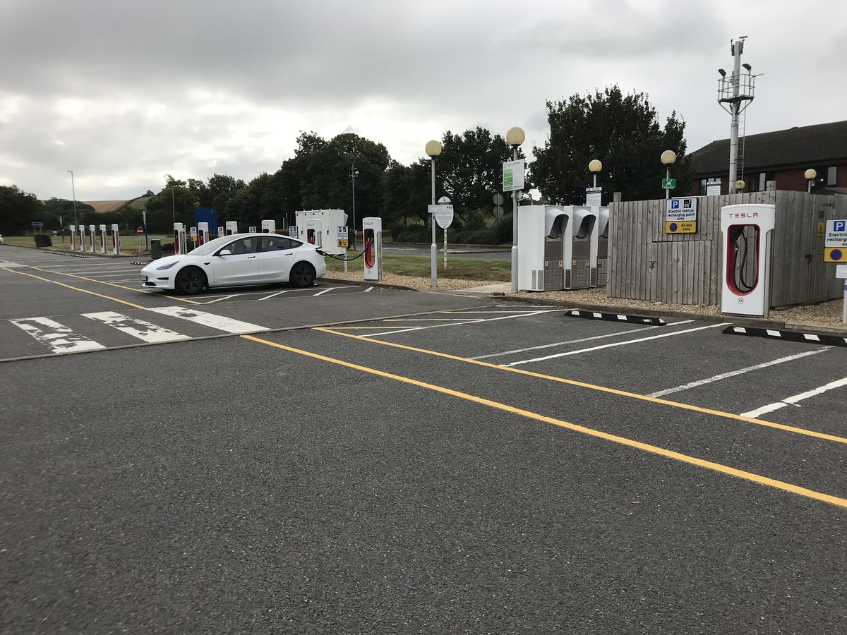 Biała Tesla Model 3 przy stacji ładowania w Anglii — rekordowy wrzesień elektryków w Wielkiej Brytanii