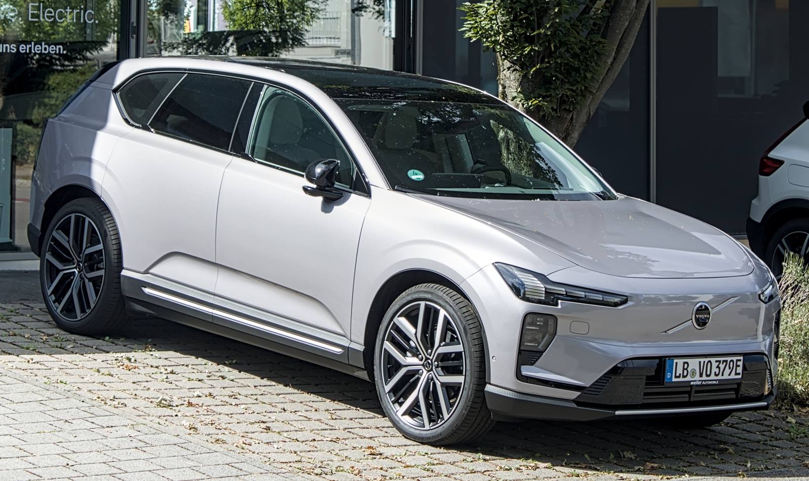 Srebrny elektryczny SUV Volvo EX60 przed salonem samochodowym