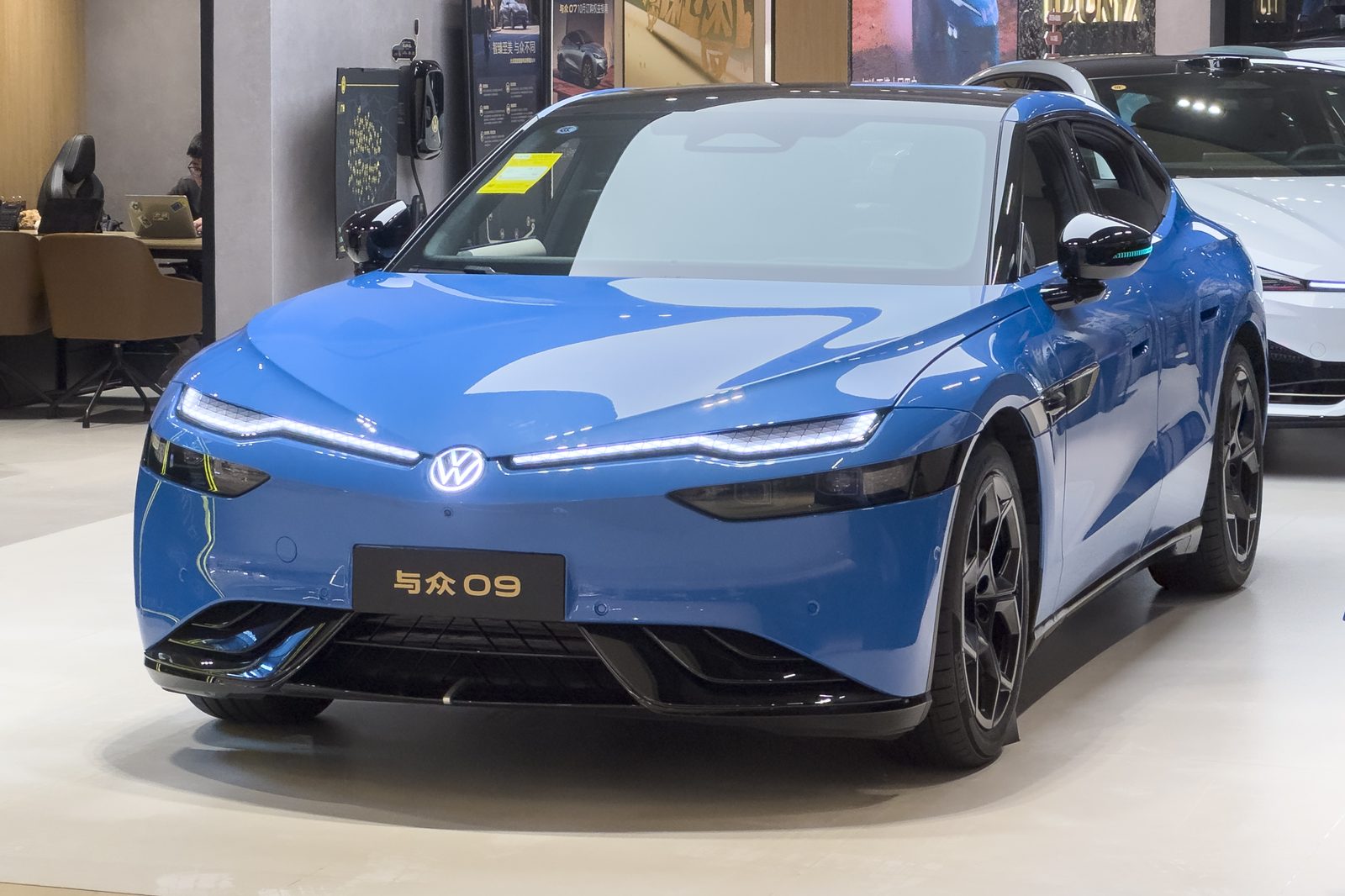 Niebieski Volkswagen ID. UNYX 09, elektryczny fastback, widziany z przodu w salonie wystawowym w Kantonie