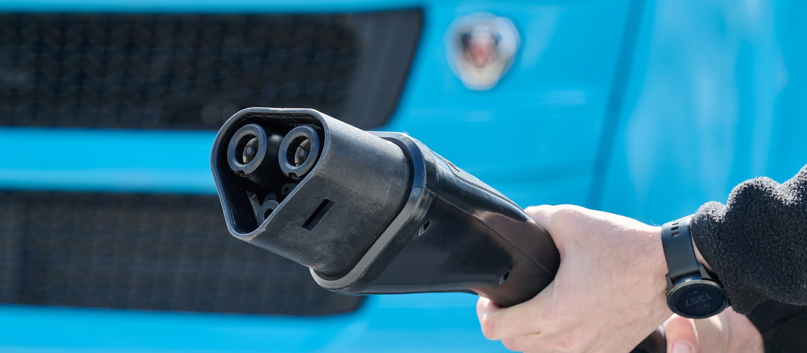 Ładowanie megawatowe MCS — wtyczka trzymana przed elektryczną ciężarówką
